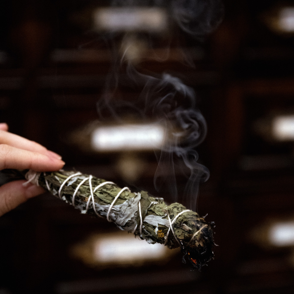 glühendes Räucherbündel in der Hand mit aufsteigendem Rauch