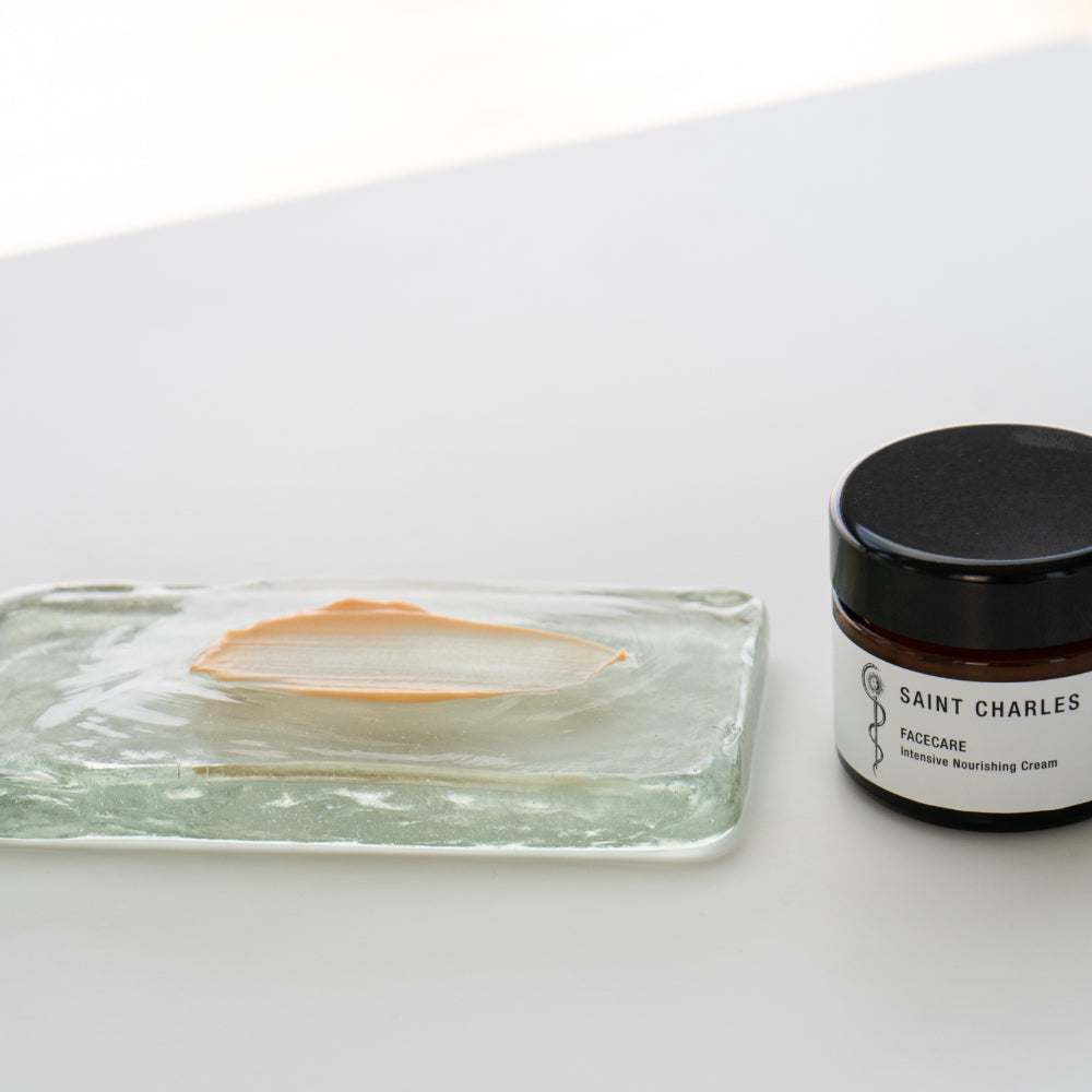 Intensive Nourishing Cream Textur auf Glasfließe aufgetragen, daneben stehend Facecare Tiegel 